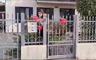 Un fermo immagine tratto da un video mostra Elena Cecchettin mettere fiocchi rossi sul cancello per festeggiare la laurea che la sorella Giulia avrebbe dovuto discutere oggi, 16 novembre 2023. ANSA/ MICHELE GALVAN