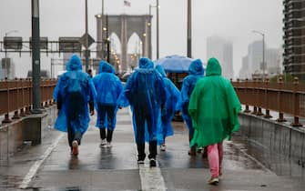 epa10890882 People walk across the Brooklyn Bridge in the heavy rain in New York, New York, USA, 29 September 2023. New York Governor Kathy Hochul declared a State of Emergency as flash flooding affects the New York City area due to heavy rain.  EPA/SARAH YENESEL