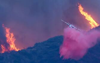 Los Angeles PACIFIC PALISADES, CALIFORNIA - JANUARY 07: A firefighting aircraft drops the fire retardant Phos-Chek as the Palisades Fire burns amid a powerful windstorm on January 7, 2025 in Pacific Palisades, California. The fast-moving wildfire is threatening homes in the coastal neighborhood amid intense Santa Ana Winds and dry conditions in Southern California. (Photo by Mario Tama/Getty Images)