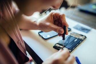 DIY repair mobile phone at home. Woman repairing mobile phone at home, changing damaged part.