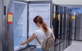 Caucasian woman chooses a refrigerator in a home appliance store