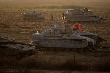 epa10918185 An Israeli soldier walks next to armored vehicles sitting in an area along the border with Gaza, southern Israel, 14 October 2023. More than 1,300 Israelis have been killed and over 3,200 others injured, according to the IDF, after the Islamist movement Hamas launched an attack against Israel from the Gaza Strip on 07 October. More than 1,500 Palestinians have been killed and over 6,600 others injured in Gaza since Israel launched retaliatory air strikes, Palestinian health officials said.  EPA/MARTIN DIVISEK