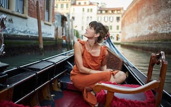 A young woman rides a gondola through Venice
