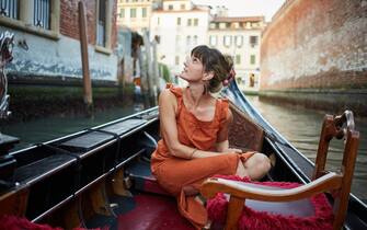 A young woman rides a gondola through Venice