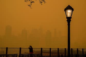 TOPSHOT - A person takes photos of the skyline as smoke from wildfires in Canada cause hazy conditions in New York City on June 7, 2023. An orange-tinged smog caused by Canada's wildfires shrouded New York on Wednesday, obscuring its famous skyscrapers and causing residents to don face masks, as cities along the US East Coast issued air quality alerts. (Photo by ANGELA WEISS / AFP)