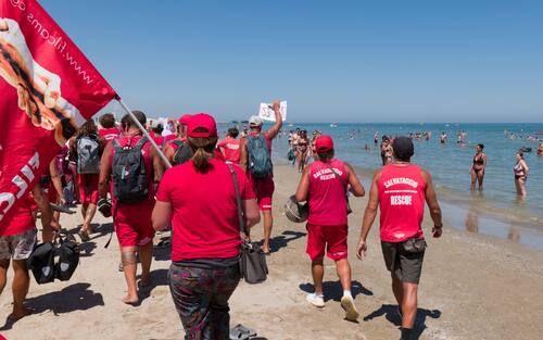 Sciopero simbolico dei bagnini oggi lungo il litorale della provincia di Rimini, dove i lavoratori del servizio di salvataggio hanno protestato per chiedere condizioni lavorative più eque. Al centro della mobilitazione, la richiesta di turni più sostenibili, nuove assunzioni e un servizio di salvataggio strutturato in maniera più sicura ed efficiente.

La protesta, indetta nel pieno della stagione estiva, non ha comportato interruzioni del servizio: grazie alla precettazione disposta dalla Prefettura, i bagnini hanno comunque garantito la sorveglianza in torretta, mentre la manifestazione si è svolta in forma ordinata.

Il corteo è partito intorno alle 12.30 dalla zona dei bagni 36-37 di Rimini, snodandosi lungo il litorale fino a raggiungere il piazzale Boscovich. Nessun disagio segnalato per i turisti presenti in spiaggia. Rimini, 9 agosto 2025. ANSA/Ph Dorin Mihai, Pasquale Bove

____

EN:

Italy: Rimini lifeguards hold symbolic strike, no impact on beach safety. Prefect orders mandatory service

RIMINI, Italy, Aug 9 (ANSA) – Lifeguards along Rimini’s coastline staged a symbolic strike on Saturday to protest working conditions during the peak summer season. The workers are demanding more manageable shift schedules, additional personnel, and improved safety protocols for rescue operations.

Despite the strike announcement, no disruption to beach safety was reported. Under an order issued by the Prefect, lifeguards were required to remain at their posts, ensuring continuous coverage of the shoreline.

The demonstration, which unfolded without incident, included a peaceful march beginning at 12:30 p.m. near Rimini bathing areas 36–37 and proceeding along the seafront to Piazzale Boscovich. Tourists and beachgoers were largely unaffected. Rimini (Italy) august 9 2025, ANSA/Ph Dorin Mihai, Pasquale Bove