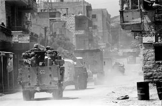 Israeli soldiers in armoured vehicles travel past houses as they pass through a village in the Bekaa Valley during the Israeli invasion of Lebanon, named "Operation Peace for the Galilee" in the Bekaa Valley, Lebanon, in June 1982. (Photo by Bryn Colton/Getty Images)