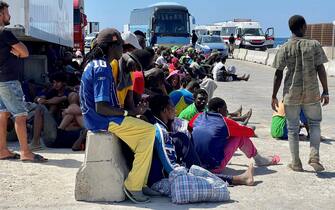 Dall'hotspot all'area di presidio dei vigili del fuoco, 400 forse 500 metri di strada - in contrada Imbriacola a Lampedusa - ricolmi di coperte termiche, scarpe, bottigliette d'acqua vuote, indumenti e tovaglie, dove aleggia un odore nauseabondo. E' un "mare umano" - scortato dai volontari della Croce Rossa - quello che anche stamattina è stato spostato perché è proprio dall'area dei vigili del fuoco che i migranti vengono caricati sugli autobus per raggiungere il porto dove verranno imbarcati su navi militari e traghetti di linea, 14 settembre 2023. ANSA/ELIO DESIDERIO