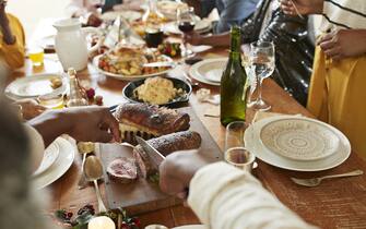 Cropped hands of mid adult man cutting meat in slices on dining table at home