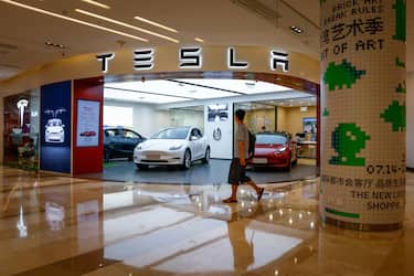 epa10794260 A man walks next to a Tesla showroom in Beijing, China, 10 August 2023 (issued 11 August 2023). China's output and sales of passenger cars went down 4.3 percent and 3.4 percent respectively in July, year-on-year, the China Association of Automobile Manufacturers said, as passenger car production reached 2.12 million units with sales hitting 2.1 million units last month.  EPA/MARK R. CRISTINO