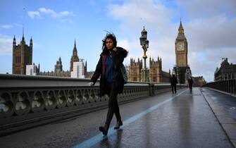 epa09768883 A woman walk across Westminster Bridge during Storm Eunice in London, Britain, 18 February 2022. The UK's Met Office has issued a red warning 'danger to life' for Storm Eunice which is causing major disruption across most parts of the UK.  EPA/ANDY RAIN