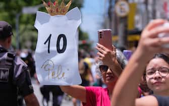03 January 2023, Brazil, Santos: Pele fans follow the parade of the coffin of the Brazilian soccer legend during the parade through the streets of Santos. The exceptional footballer Pele died on 29.12.2022 at the age of 82 in Sao Paulo. Photo: Lincon Zarbietti/dpa