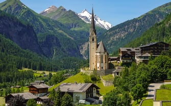 21 July 2021, Austria, Heiligenblut: The Gothic pilgrimage church in Heiligenblut is dedicated to St. Vincent of Saragossa and behind the tower you can see the snow-covered peak of the GroÃ glockner. The GroÃ glockner is 3,798 metres high, making it the highest mountain in the Alpine region of Austria. It is located in the center of the largest Austrian national park Hohe Tauern. Photo: Patrick Pleul/dpa-Zentralbild/ZB (Photo by Patrick Pleul/picture alliance via Getty Images)