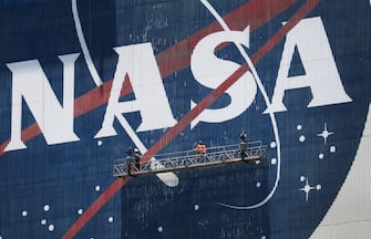 CAPE CANAVERAL, FLORIDA - MAY 20: Workers freshen up the paint on the NASA logo on the Vehicle Assembly Building before the arrival of NASA astronauts Bob Behnken and Doug Hurley at the Kennedy Space Center on May 20, 2020 in Cape Canaveral, Florida.  The astronauts are scheduled to arrive today for the May 27th flight of SpaceXâ  s Crew Dragon spacecraft. They will be the first people since the end of the Space Shuttle program in 2011 to be launched into space from the United States. (Photo by Joe Raedle/Getty Images)