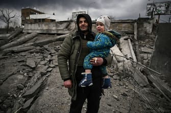 TOPSHOT - A man holds a child as he flees the city of Irpin, west of Kyiv, on March 7, 2022. - Russian forces pummelled Ukrainian cities from the air, land and sea on Monday, with warnings they were preparing for an assault on the capital Kyiv, as terrified civilians failed for a second day to escape besieged Mariupol. (Photo by ARIS MESSINIS / AFP) (Photo by ARIS MESSINIS/AFP via Getty Images)