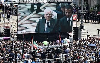 A view shows a live broadcast of Italian president Sergio Mattarella (C) and Qatari emir Sheikh Tamim bin Hamad Al-Thani inside the Duomo cathedral, on a giant screen installed at Piazza Duomo in Milan on June 14, 2023 for people to follow the state funeral for Italy's former prime minister and media mogul Silvio Berlusconi. (Photo by GABRIEL BOUYS / AFP) (Photo by GABRIEL BOUYS/AFP via Getty Images)