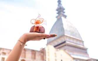 Holding italian chocolate with bow on famous cinema tower background in Turin city. Turin in Piedmont region in Italy is famous of its chocolate making