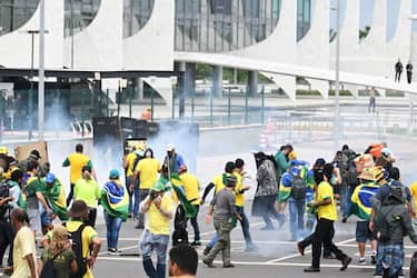 Supporters of Brazilian former President Jair Bolsonaro clash with the police during a demonstration outside the Planalto Palace in Brasilia on January 8, 2023. - Brazilian police used tear gas Sunday to repel hundreds of supporters of far-right ex-president Jair Bolsonaro after they stormed onto Congress grounds one week after President Luis Inacio Lula da Silva's inauguration, an AFP photographer witnessed. (Photo by EVARISTO SA / AFP) (Photo by EVARISTO SA/AFP via Getty Images)