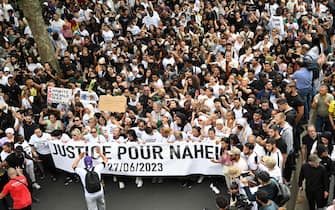 Attendees hold a banner reading "Justice for Nahel", during a commemoration march for a teenage driver shot dead by a policeman, in the Parisian suburb of Nanterre, on June 29, 2023. Violent protests broke out in France in the early hours of June 29, 2023, as anger grows over the police killing of a teenager, with security forces arresting 150 people in the chaos that saw balaclava-clad protesters burning cars and setting off fireworks. Nahel M., 17, was shot in the chest at point-blank range in Nanterre in the morning of June 27, 2023, in an incident that has reignited debate in France about police tactics long criticised by rights groups over the treatment of people in low-income suburbs, particularly ethnic minorities. (Photo by Bertrand GUAY / AFP)