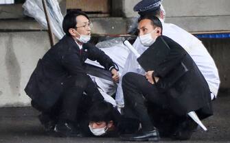 A man (bottom) is detained after throwing an apparent"smoke bomb" in Wakayama on April 15, 2023, where Japan's Prime Minister was due to give a speech. - Kishida was evacuated from the port in Wakayama after a blast was heard, but he was unharmed in the incident, local media reported on April 15. (Photo by JIJI Press / AFP) / Japan OUT (Photo by STR/JIJI Press/AFP via Getty Images)