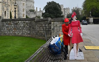 A photograph taken on March 31, 2024 shows cardboards depicting Britain's Catherine, Princess of Wales (R) and Britain's King Charles III placed in front of Windsor Castle as Britain's royal family prepares to attend the Easter Mattins Service at St. George's Chapel, Windsor Castle. (Photo by JUSTIN TALLIS / AFP)