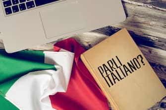 A computer, flag of Italy and book titled Speak Italian