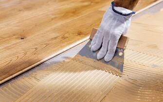 worker apply adhesive for 3 layer parquet flooring
