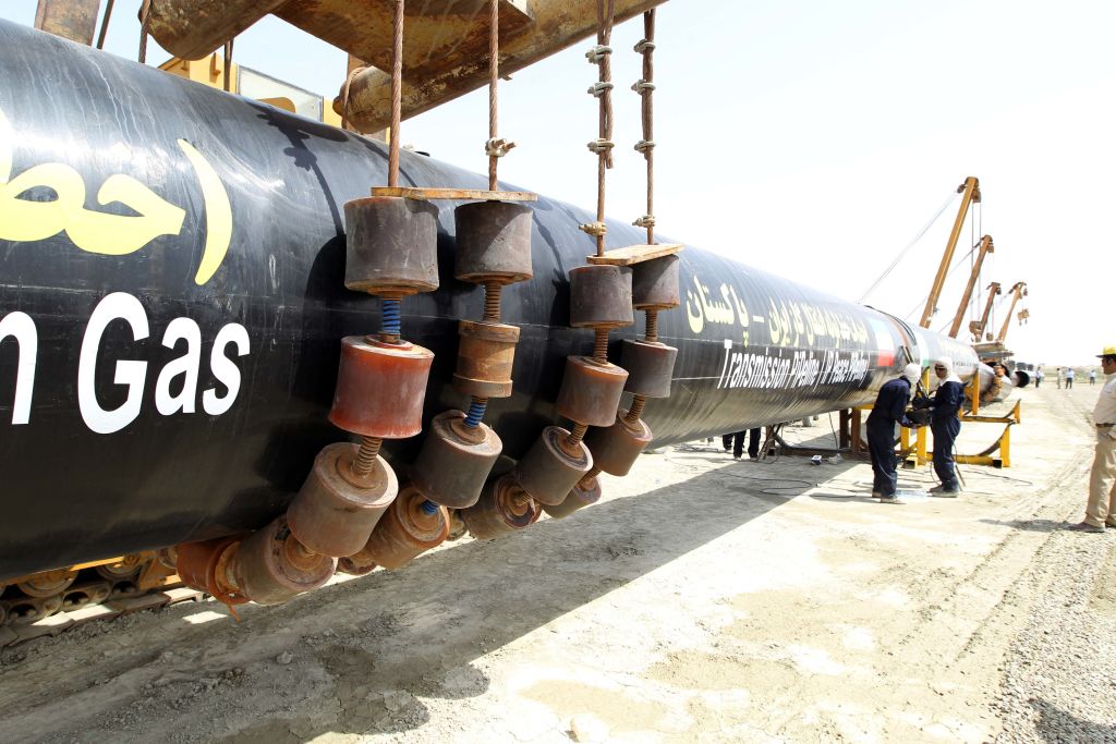 Iraniaswork on a section of a pipeline after the project was launched during a ceremony with presidents of Iran and Pakistan on March 11, 2013 in the Iranian border city of Chah Bahar. The two leaders jointly unveiled a plaque before shaking hands and offering prayers for the successful conclusion of the project, which involves the laying of a 780 kilometre (485 mile) section of the pipeline on the Pakistani side, expected to cost some $1.5 billion.  AFP PHOTO/ATTA KENARE (Photo by Atta KENARE / AFP) (Photo by ATTA KENARE/AFP via Getty Images)