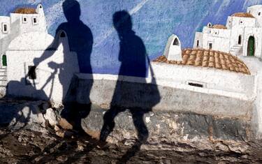 Shadow of a man and woman with a baby stroller on a mural in Peschici