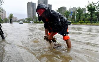 FUZHOU, CHINA - JULY 29: A worker cleans a manhole cover in a flooded street on July 29, 2023 in Fuzhou, Fujian Province of China. Typhoon Doksuri made landfall in the coastal areas of Jinjiang, Quanzhou City, Fujian Province at around 9:55 a.m. on July 28. (Photo by Lyu Ming/China News Service/VCG via Getty Images)