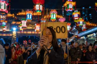 A woman is offering a burning incense stick at Wong Tai Sin Temple in Hong Kong, on February 9, 2024. Hundreds are waiting in line at the temple to offer their first incense of the Year of the Dragon in the zodiac calendar. (Photo by Vernon Yuen/NurPhoto via Getty Images)
