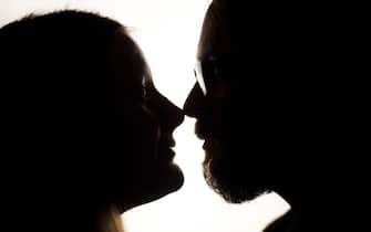 Silhouette of a couple looking into each other's eyes, in profile. Their noses are touching.