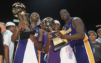 EAST RUTHERFORD, NJ - JUNE 12:  Guard Kobe Bryant #8 of the Los Angeles Lakers holds up the championship trophy as center Shaquille O'Neal #34 hands his Finals Series MVP trophy to guard Lindsey Hunter #10 after winning Game Four of the 2002 NBA Finals against the New Jersey Nets at Continental Airlines Arena in East Rutherford, New Jersey on June 12, 2002. The Lakers defeated the Nets 113-107 and won the series 4-0. NOTE TO USER: User expressly acknowledges and agrees that, by downloading and/or using this Photograph, User is consenting to the terms and conditions of the Getty Images License Agreement Mandatory Copyright Notice: Copyright 2002 NBAE (Photo by Nathaniel S. Butler/NBAE via Getty Images)