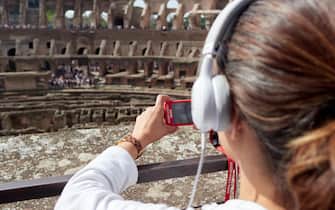 Tourist women listen the audioguide while visiting the Colosseum in Rome, Italy.