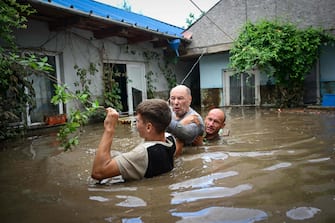 TOPSHOT - Local residents rescue an elderly man (C) from the rising flood waters in the Romanian village of Slobozia Conachi on September 14 2024. Storm Boris killed four people in Romania on September 14 2024, as exceptional rains caused flooding in several countries in central and eastern Europe.
Romanian rescue services announced that they had found the bodies of four people during a search operation in the worst-hit region, Galati (southeast), where 5,000 homes were affected. (Photo by Daniel MIHAILESCU / AFP)