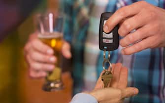 Man gives his car keys to a designated driver friend after he has been drinking too much at nightclub.  Beer glass. 
