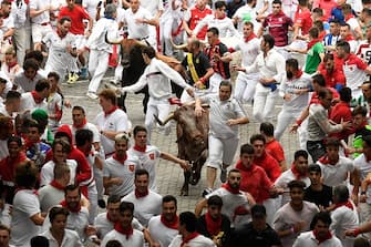 Participants run ahead of bulls during the first "encierro" (bull-run) of the San Fermin festival in Pamplona, northern Spain, on July 7, 2023. Thousands of people every year attend the week-long festival and its famous 'encierros': six bulls are released at 8:00 a.m. evey day to run from their corral to the bullring through the narrow streets of the old town over an 850 meters (yard) course while runners ahead of them try to stay close to the bulls without falling over or being gored. (Photo by MIGUEL RIOPA / AFP) (Photo by MIGUEL RIOPA/AFP via Getty Images)