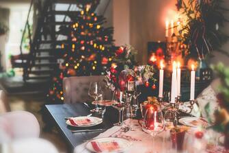 Christmas dinner table at festive cozy room background with Christmas tree and candle lighting. Indoor