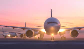 Airplanes taxiing on runway at sunset