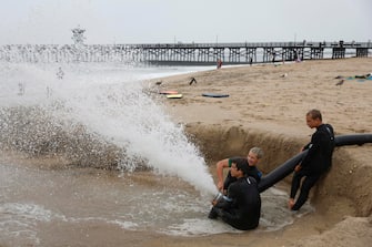 Dei ragazzi spurgano l'acqua in spiaggia con un grosso tubo in California