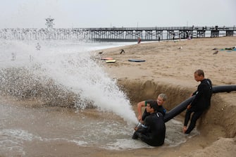 epa10811121 People play with a drainage hose on the beach in Seal Beach, California, USA, 20 August 2023. Southern California is under a tropical storm warning for the first time in history as Hilary makes landfall. The last time a tropical storm made landfall in Southern California was 15 September 1939, according to the National Weather Service.  EPA/CAROLINE BREHMAN