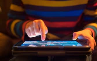 Close up of a young boy using a tablet computer, his finger hovering over it as he's about to touch the screen.