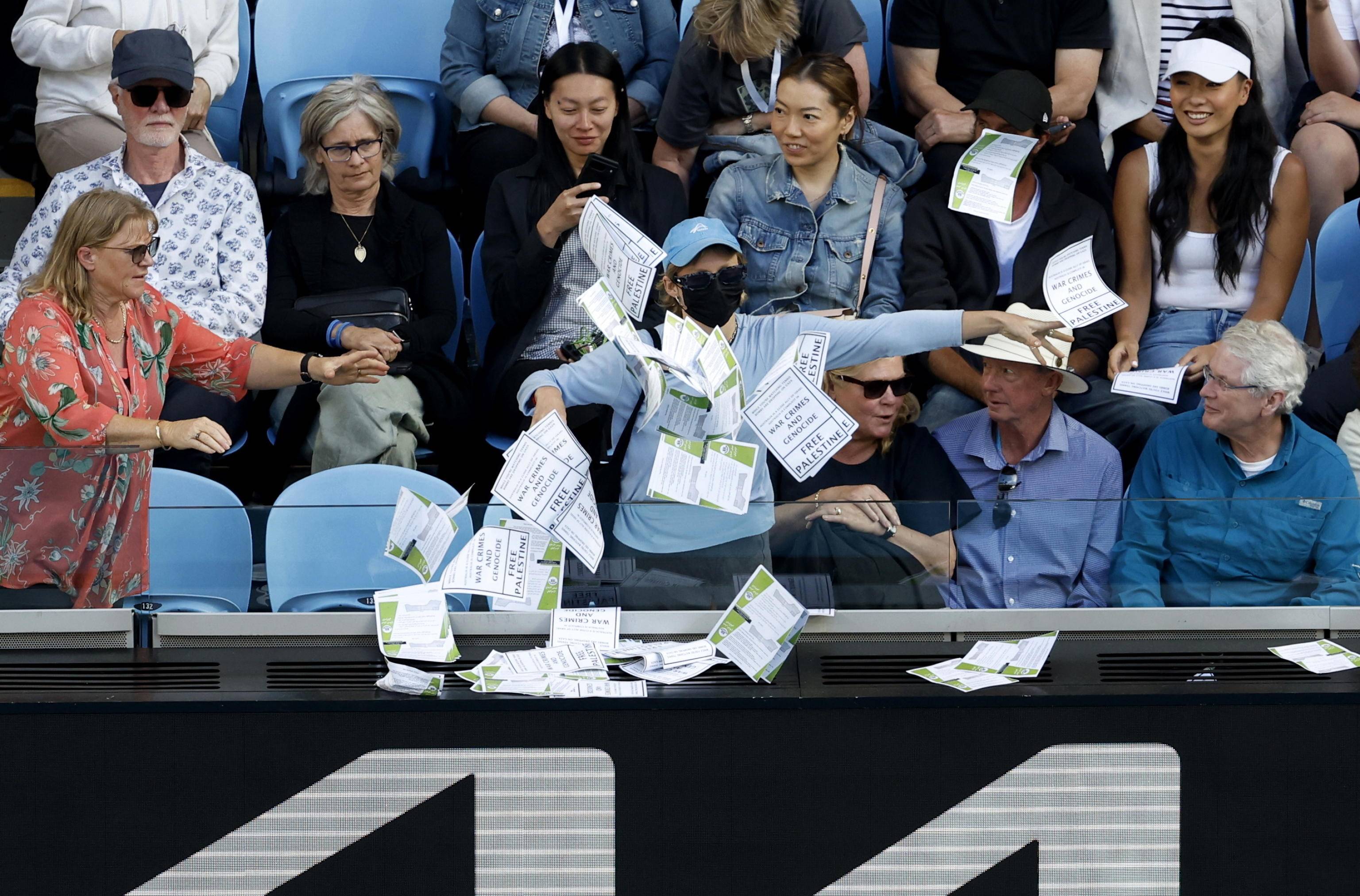 epa11095474 A woman throws papers that read 'Free Palestine' during the men's fourth round match between Alexander Zverev of Germany and Cameron Norrie of Britain at the Australian Open tennis tournament in Melbourne, Australia, 22 January 2024.  EPA/MAST IRHAM