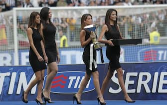 491956803 Hostesses enter the field with the trophy and the medal before the trophy ceremony of the Italian Serie A after the last football game of the season Juventus vs Cagliari on May 18, 2014 at the Juventus Stadium in Turin. Juventus won their third consecutive "scudetto". AFP PHOTO / MARCO BERTORELLO (Photo credit should read MARCO BERTORELLO/AFP via Getty Images)