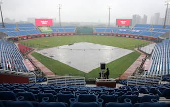 1209662622 A masked broadcaster stands by at the Taoyuan Baseball stadium before the opening match for the Chinese Professional Baseball League (CPBL) in Taoyuan on April 11, 2020. - The match is called off due to the heavy rain. (Photo by Alex Lee / AFP) (Photo by ALEX LEE/AFP via Getty Images)