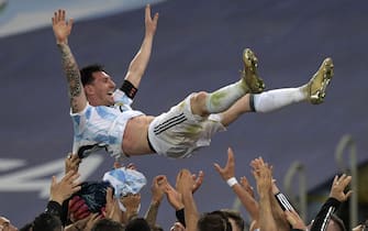 TOPSHOT - Argentina's Lionel Messi is thrown into the air by teammates after winning the Conmebol 2021 Copa America football tournament final match against Brazil at Maracana Stadium in Rio de Janeiro, Brazil, on July 10, 2021. - Argentina won 1-0. (Photo by CARL DE SOUZA / AFP) (Photo by CARL DE SOUZA/AFP via Getty Images)