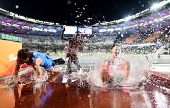 epa10814562 (from L) Men's High Jump gold medalist Gianmarco Tamberi of Italy, Men's 3000m Steeplechase bronze medalist Abraham Kibiwot of Kenya and Men's 3000m Steeplechase gold medalist Soufiane El Bakkali of Morocco celebrate in the Steeplechase water pit at the World Athletics Championships Budapest, Hungary, 22 August 2023.  EPA/CHRISTIAN BRUNA