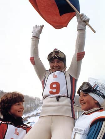 Hanni Wenzel from Liechtenstein, carried by Erika Hess (L) from Switzerland and Christa Kinshofer from West Germany, waves a country flag as she celebrates her victory in the women's slalom, 23 February 1980 in Lake Placid at the Winter Olympic Games. Wenzel set the fastest times in both runs to win the gold medal in front of Kinshofer (silver) and Hess (bronze). During the skiing competition in Lake Placid, Hanni Wenzel won two gold medals (slalom and giant slalom) and a silver medal (downhill). AFP PHOTO/EPU (Photo by STAFF / EPU / AFP) (Photo by STAFF/EPU/AFP via Getty Images)