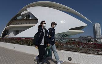 A couple wearing protective masks walk at the City of Arts and Sciences in Valencia on March 14, 2020 as Spain confirmed more than 1,500 new cases of coronavirus between Friday and Saturday raising its total to 5,753 cases, the second-highest number in Europe after Italy. - The country is expected to declare a state of alert to try to mobilise resources to combat the virus, which has so far killed 136 people in Spain. (Photo by JOSE JORDAN / AFP) (Photo by JOSE JORDAN/AFP via Getty Images)