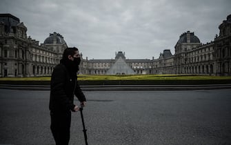 A man wearing a protective mask ride an eletric scooter in front of the Louvre palace in Paris, on March 18, 2020,  as a strict lockdown came into in effect in France to stop the spread of COVID-19, caused by the novel coronavirus. - A strict lockdown requiring most people in France to remain at home came into effect at midday on March 17, 2020, prohibiting all but essential outings in a bid to curb the coronavirus spread. The government has said tens of thousands of police will be patrolling streets and issuing fines of 135 euros ($150) for people without a written declaration justifying their reasons for being out (Photo by Philippe LOPEZ / AFP) (Photo by PHILIPPE LOPEZ/AFP via Getty Images)